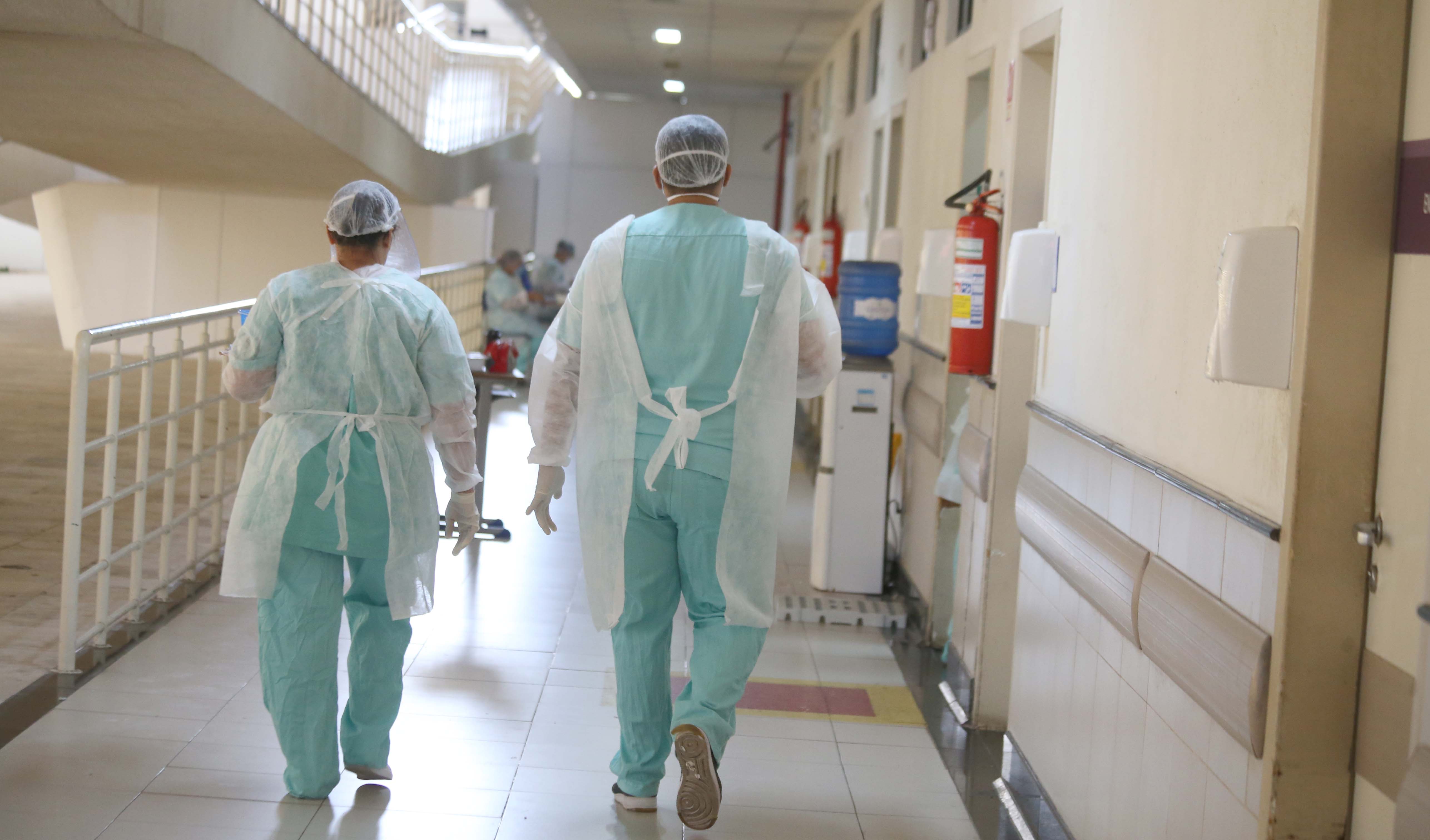 Um enfermeiro e uma enfermeira caminham de costas num corredor do Hospital da Mulher